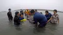 Relawan ThaiWhales dan dokter hewan berupaya menyelamatkan paus pilot jantan yang sakit dan tidak bisa berenang di pesisir pantai di Songkhla, Thailand, Sabtu (2/6). Sekitar 80 kantong plastik ditemukan di dalam perut paus tersebut. (AFP/ThaiWales)