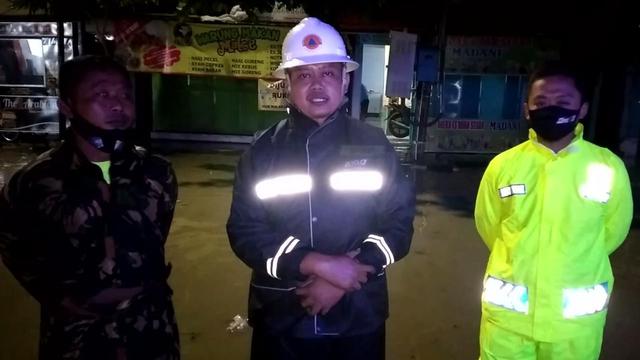 Ketua TRC BPBD Blora, Agung Tri didampingi pihak Koramil dan Polsek Cepu ketika diwawancarai awak media di lokasi banjir wilayah Kelurahan Cepu, Kecamatan Cepu, Kabupaten Blora. (Liputan6.com/Ahmad Adirin)