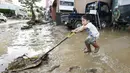 Seorang bocah membantu membersihkan kotoran di depan rumah kakek dan neneknya setelah hujan lebat di Hitoyoshi, Prefektur Kumamoto, Jepang, Sabtu (4/7/2020). Hujan deras memicu banjir dan tanah longsor di sejumlah wilayah Jepang. (Yuki Sato/Kyodo News via AP)