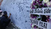 Karangan bunga diletakkan di sisi banner tulisan dukungan buat Polri pasca kerusuhan di Rutan cabang Salemba Mako Brimob saat acara Car Free Day di Kawasan Bundaran Hotel Indonesia, Jakarta, Minggu (13/5). (Liputan6.com/Helmi Fithriansyah)