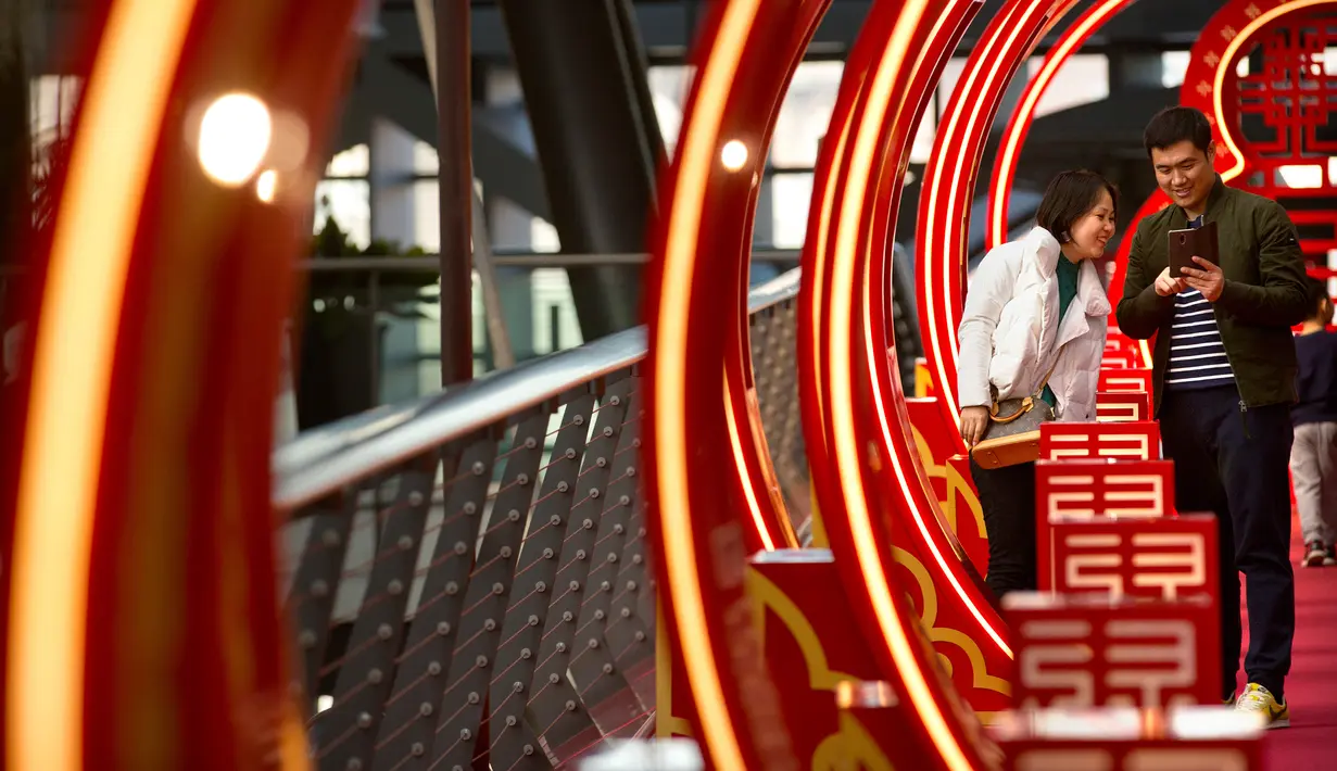 Pengunjung berfoto di sebuah jembatan bertema Imlek di sebuah pusat perbelanjaan kelas atas di Beijing (21/2). Jembatan berwarna merah yang bertema Imlek ini menjadi pusat perhatian dan tempat berfoto pengunjung. (AP Photo / Mark Schiefelbein)