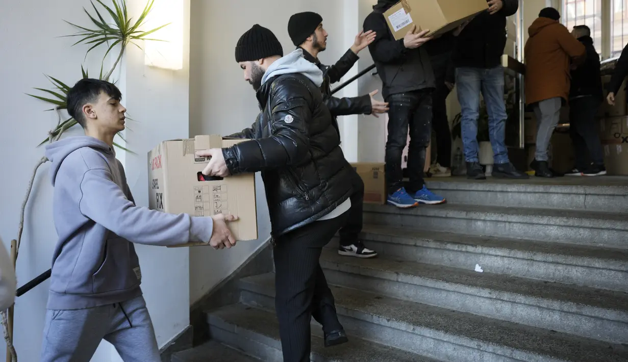 Orang-orang menumpuk kotak berisi persediaan bantuan di tempat pengumpulan komunitas Turki di Berlin, Jerman, Selasa, 7 Februari 2023. Ratusan anggota komunitas Turki Berlin berbondong-bondong ke sekolah musik di ibu kota Jerman untuk menyumbangkan bantuan kemanusiaan penting setelah Turki selatan dan Suriah utara dilanda gempa bumi ganda pada Senin, 6 Februari 2023. (AP Photo/Markus Schreiber)