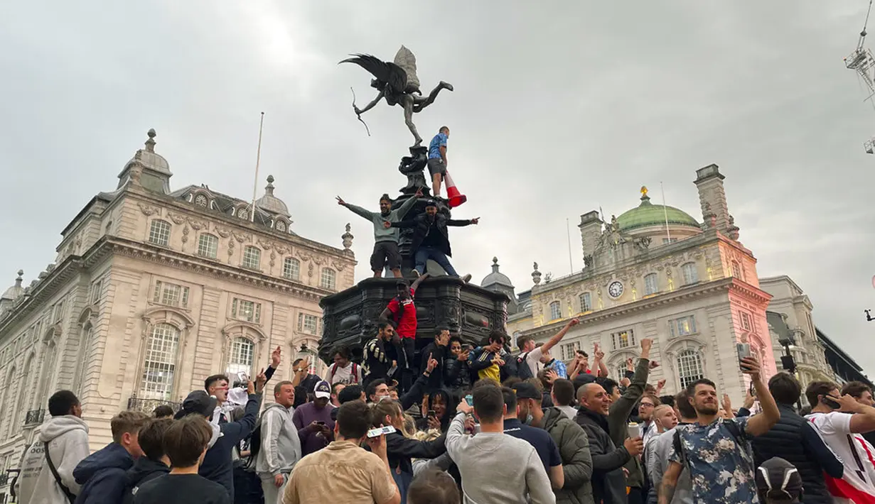 Suporter Inggris memanjat patung Eros di Piccadilly Circus saat merayakan kemenangan Inggris atas Jerman pada pertandingan babak 16 besar Euro 2020 di London, Inggris, Selasa (29/6/2021). nggris menang 2-0. (Isobel Frodsham/PA via AP)