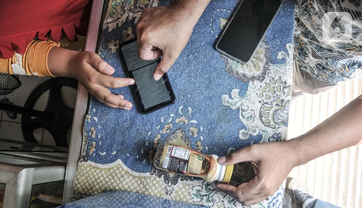 Petugas mendampingi warga saat memindai sampah botol melalui aplikasi smartphone sebelum ditabung ke ATM Sampah Keliling di kawasan Semper Barat, Cilincing, Jakarta Utara, Selasa (12/10/2021). (merdeka.com/Iqbal S. Nugroho)