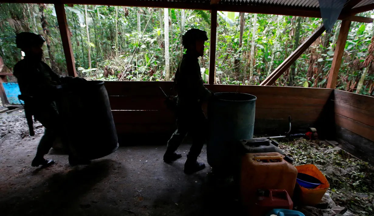 Polisi antinarkotika Kolombia mengangkat tong di laboratorium pembuatan kokain di tengah hutan, Desa Calamar, Guaviare, Kolombia, Selasa (2/8). Polisi mengaku sudah memusnahkan 104 pabrik kokain dalam operasi 5 hari.(REUTERS/John Vizcaino)