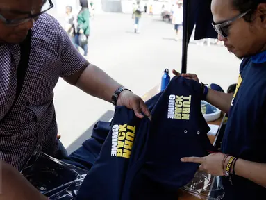 Calon pembeli melihat baju bertulisan "Turn Back Crime" yang dijual saat Car Free Day dikawasan Bunderan HI, Jakarta, Minggu (13/3). Penggunaan merk 'Turn Back Crime' bertujuan untuk kampanye waspada tindak kejahatan. (Liputan6.com/Faizal Fanani)