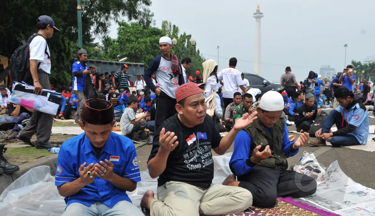 Para buruh berdoa bersama usai melaksanakan salat Jumat di kawasan Monas, Jakarta, Jum'at (1/5/2015). Lebih dari 100.000 buruh ikut dalam aksi May Day.(Liputan6.com/Andrian M Tunay) 