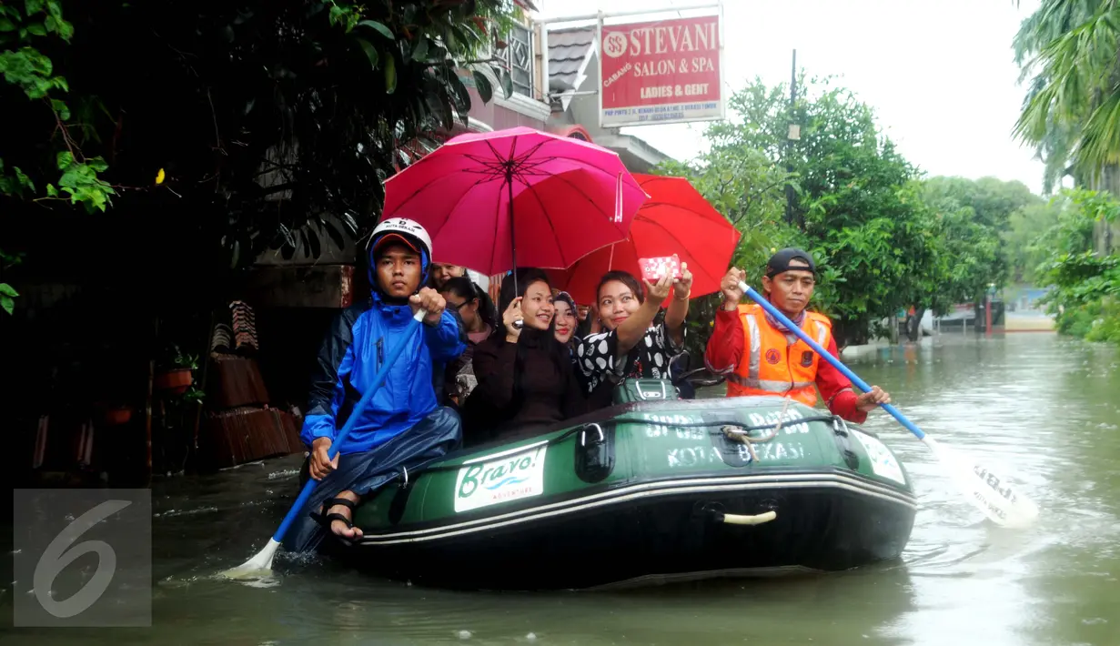 Sejumlah warga selfie diatas perahu karet saat dievakuasi petugas di perumahan Pondok Hijau Permai, Bekasi. (Liputan6.com/Gempur M. Surya)