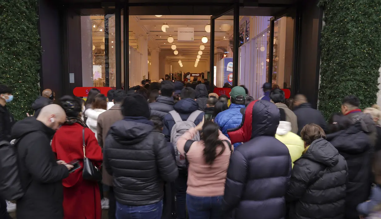 Kerumunan arus pembeli melalui pintu masuk saat dibuka untuk memulai penjualan Boxing Day di department store Selfridges di Oxford Street, London, Minggu (26/12/2021).  'Boxing Day' adalah hari saat toko-toko di Inggris menggelar diskon besar-besaran, sehari setelah Natal. (Jonathan Brady/PA via AP)