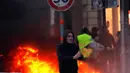 Demonstran berjalan dekat api saat kerusuhan menentang kenaikan harga bahan bakar di Paris, Prancis, Sabtu (24/11). Demonstran tersulut oleh hasutan beberapa oknum sehingga memicu kerusuhan. (AP Photo/Christophe Ena)