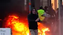 Demonstran berjalan dekat api saat kerusuhan menentang kenaikan harga bahan bakar di Paris, Prancis, Sabtu (24/11). Demonstran tersulut oleh hasutan beberapa oknum sehingga memicu kerusuhan. (AP Photo/Christophe Ena)
