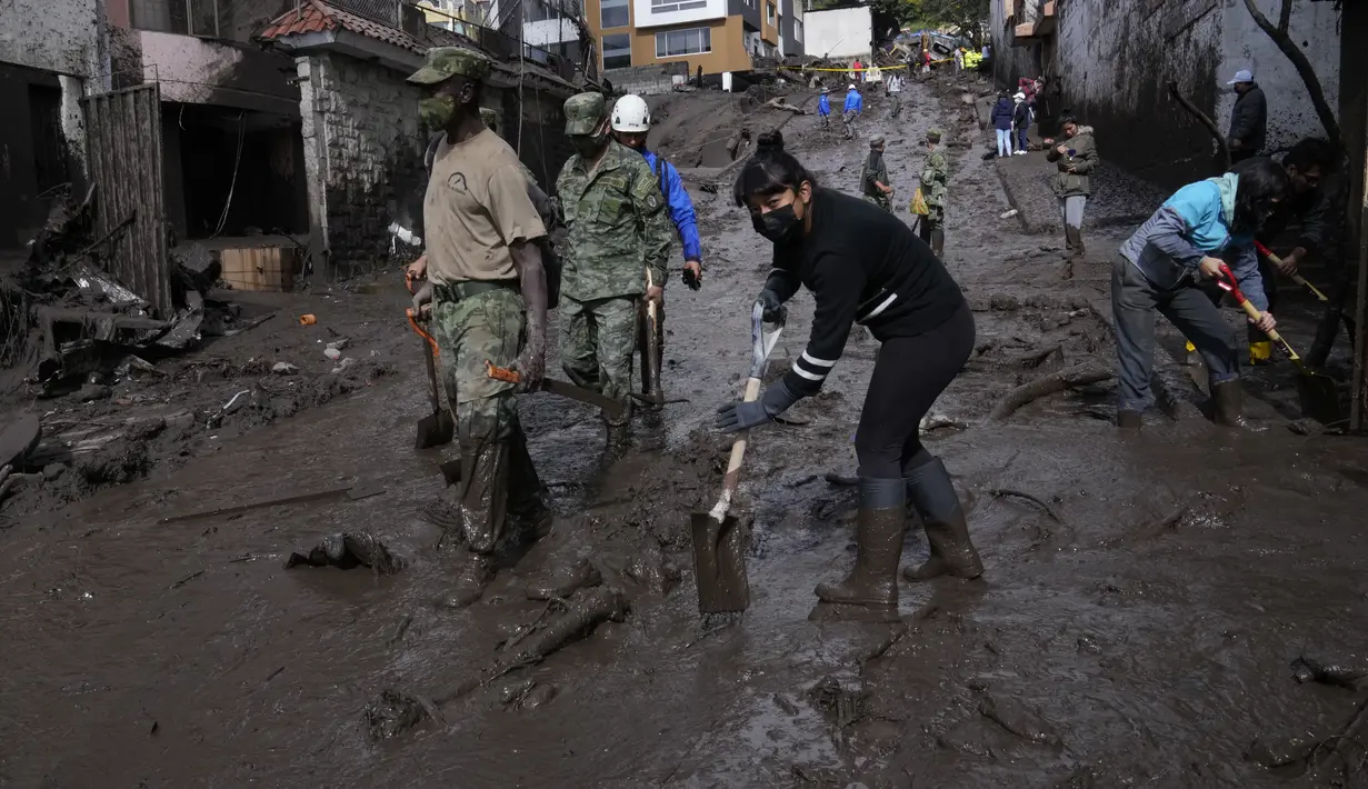 Warga dan tentara bekerja untuk membersihkan lumpur dari jalan-jalan setelah lereng bukit yang diguyur hujan runtuh dan membawa gelombang lumpur ke daerah La Gasca di Quito, Ekuador, Selasa (1/2/2022). (AP Photo/Dolores Ochoa)