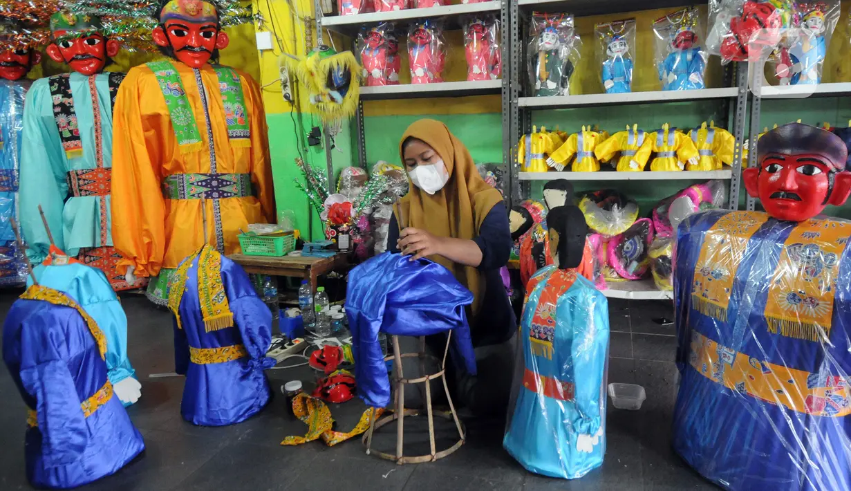 Pekerja membuat ondel-ondel di Rumah Produksi Ondel-Ondel Jakarta, Setu Babakan, Jakarta Selatan, Minggu (19/9/2021). Setelah stagnan selama dua tahun akibat pandemi COVID-19, produksi dan penjualan ondel-ondel pasca PPKM Level 3 mengalami kenaikan hingga 20 persen. (merdeka.com/Arie Basuki)