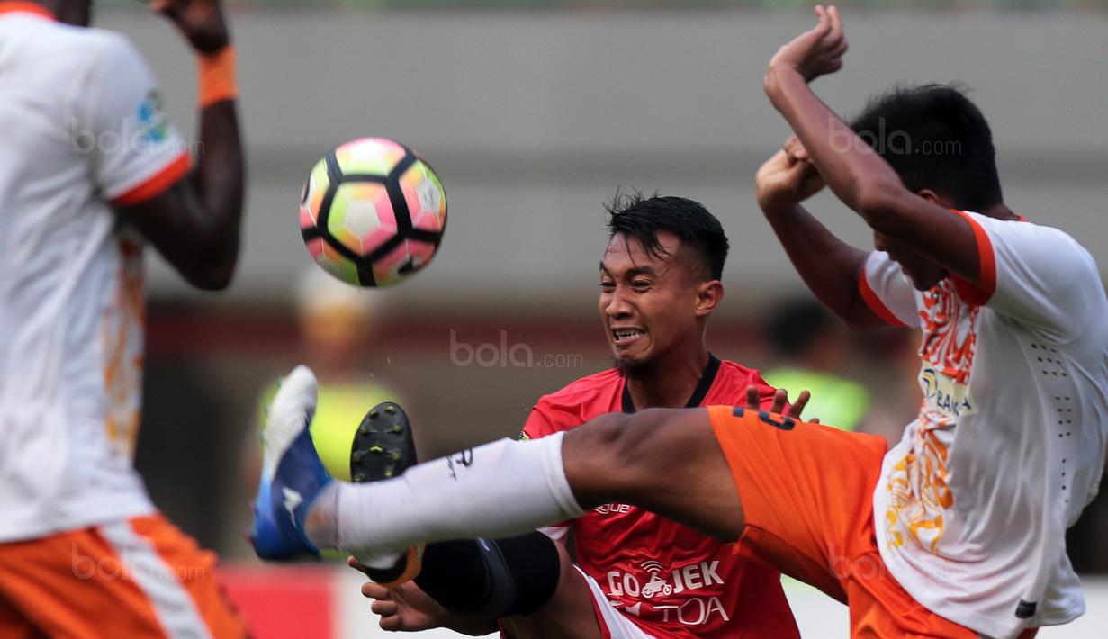 Duel pemain Persija Jakarta, Hargianto (tengah) dan pemain Perseru Serui, Zaenuri (kanan) pada lanjutan Liga 1 2017 di Stadion Patriot Bekasi, Selasa (19/9/2017). Persija menang 1-0. (Bola.com/Nicklas Hanoatubun)