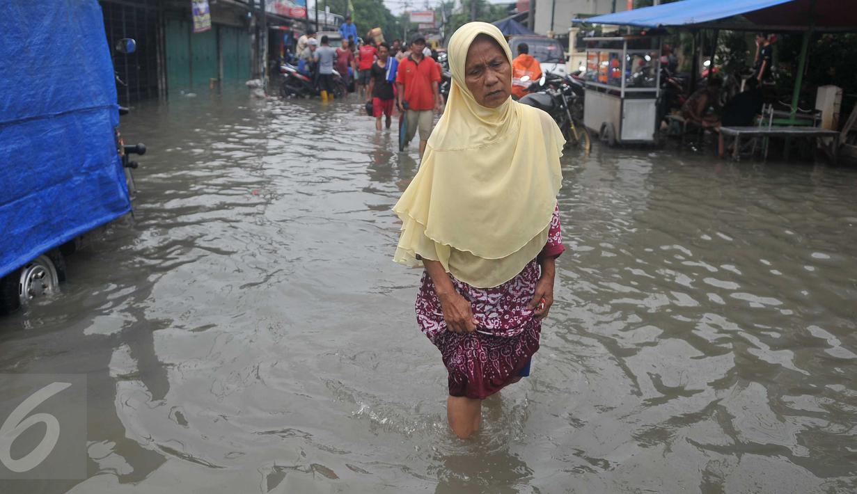 Seorang wanita melintas saat banjir melanda kawasan Rawa Buaya, Jakarta, Minggu (28/2/2016). Rawa Buaya menjadi kawasan banjir terparah hingga mencapai 1 meter. (Liputan6.com/Gempur M Surya)