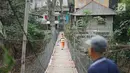 Seorang anak melintasi jembatan gantung semi permanen di kawasan Srengseng Sawah, Jakarta Selatan, Sabtu (24/8/2019). Jauhnya akses penyeberangan lain menyebabkan warga terpaksa memanfaatkan jembatan tersebut untuk menyeberangi Sungai Ciliwung. (Liputan6.com/Immanuel Antonius)