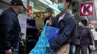 Seorang pria dengan mengenakan masker wajah seusai membeli kertas tisu di luar apotek di Hong Kong, Kamis (6/2/2020). Di tengah kelangkaan masker wajah untuk melindungi terhadap wabah virus corona, tisu toilet tiba-tiba juga menjadi salah satu barang yang langka di Hong Kong. (AP/Vincent Yu)