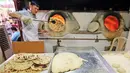 Tukang roti mengangkat roti Iran atau taftoon setelah dipanggang dalam oven tradisional di sebuah toko di Kuwait City, Kuwait, 27 Juni 2019. Beberapa orang Kuwait biasanya menambahkan taftoon dengan wijen, thyme, adas, hingga kurma. (YASSER AL-ZAYYAT/AFP)