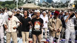 Massa aksi melaksanakan salat Ashar di sela unjuk rasa di Kawasan Patung Kuda, Jakarta, Selasa (13/10/2020). Massa aksi menolak Undang-Undang Cipta Kerja Omnibus Law tersebut salat beralaskan spanduk, kardus, hingga sajadah. (Liputan6.com/Faizal Fanani)