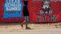 Seorang lelaki Indonesia yang mengenakan masker berjalan melewati mural di tengah kekhawatiran pandemi Virus Corona COVID-19 di Tangerang. (Fajrin Raharjo / AFP)