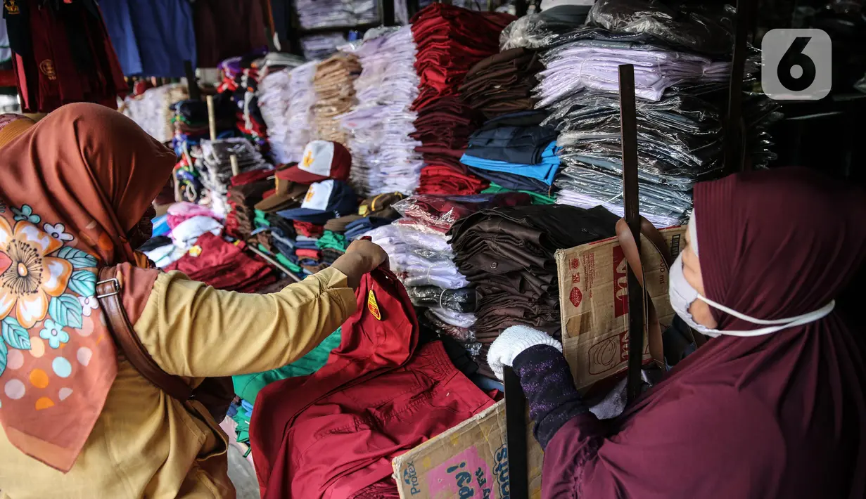Calon pembeli melihat seragam sekolah di kawasan Pasar Jatinegara, Jakarta, Selasa (30/6/2020). Sejumlah pedagang di tempat itu mengeluhkan omset penjualan seragam sekolah yang menurun hingga 90 persen akibat sepi pembeli dan anjuran belajar di rumah saat  COVID-19. (Liputan6.com/Faizal Fanani)