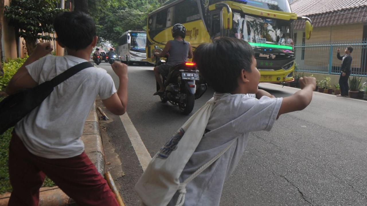 Sejumlah anak berjoget ketika mendengarkan klakson telolet atau klakson tidak standar, yang biasanya mengeluarkan nada-nada tak biasa, dari sebuah bus yang meninggalkan kawasan Taman Margasatwa Ragunan, Jakarta, Kamis (13/6/2024). Meski mengancam nyawa, n