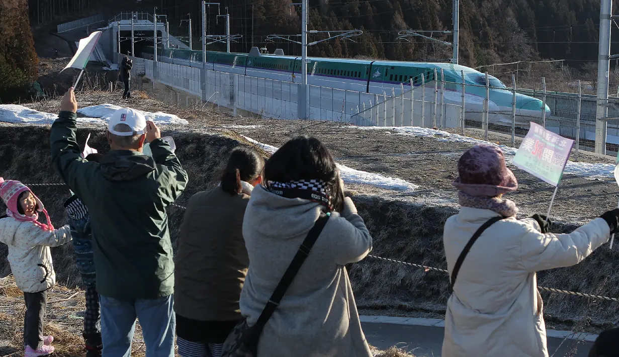 Warga saat menyambut dengan meriah kereta peluru Shinkansen tujuan Shin-hakodate-Hokuto di stasiun Tokyo, Sabtu (26/3). Warga Jepang bersuka cita karena diresmikannya jalur kereta peluru Shinkansen menuju pulau utara Hokkaido. (JIJI PRESS / AFP)