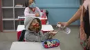 Seorang siswa mendapat semprotan gel anti bakteri dari gurunya pada hari pertama kembali ke kelas tatap muka di tengah pandemi COVID-19 di sekolah umum Raul Antonio Fragoso di Sao Paulo, Brasil (8/2/2021).  Sekolah tatap muka diizinkan dengan maksimal 35% siswanya. (AP Photo/Andre Penner)