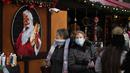 Orang-orang melewati gambar Sinterklas di sisi sebuah kios di pasar Natal, di Trafalgar Square, London, Senin (29/11/2021). Di Inggris, kewajiban mengenakan masker akan berlaku lagi di toko-toko dan transportasi umum mulai Selasa menyusul temuan Covid-19 varian Omicron. (AP Photo/Matt Dunham)