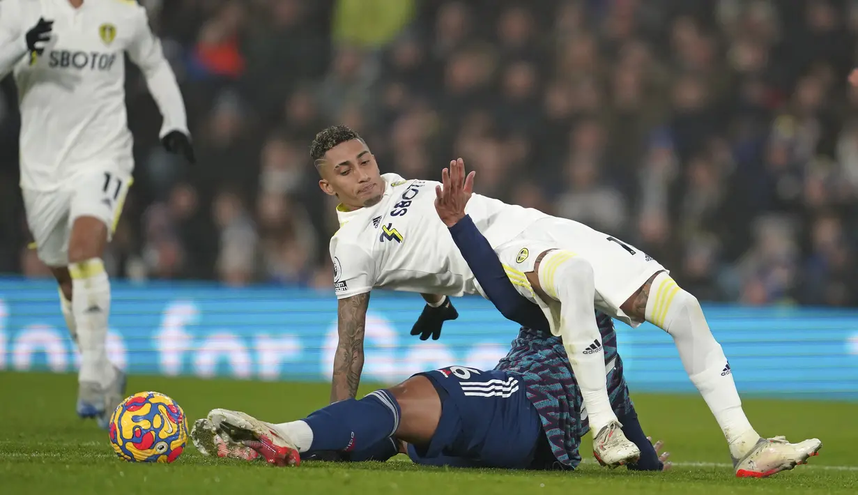 Penyerang Leeds United Raphinha (atas) berebut bola dengan bek Arsenal Gabriel pada pekan ke-18 Liga Inggris di Stadion Ellan Road, Leeds, Minggu (19/12/2021) dini hari WIB. Arsenal menang 4-1 di kandang Leeds United. (AP Photo/Jon Super)