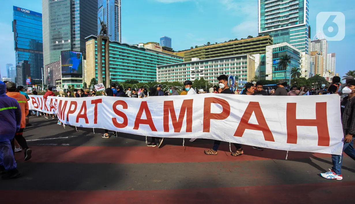 Pengunjung melintas saat warga dari Komunitas Peduli Sampah menggelar aksi saat Hari Bebas Kendaraan Bermotor di Bundaran HI, Jakarta, Minggu (26/6/2022). Kampanye tentang sampah tersebut dalam rangka melanjutkan Pekan Gerakan Jakarta Sadar Sampah yang menghimbau masyarakat untuk saling menjaga kebersihan lingkungan. (Liputan6.com/Johan Tallo)