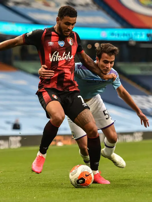 Pemain Bournemouth Joshua King berusaha mengontrol bola dari kawalan pemain Manchester City, Eric Garcia pada pertandingan lanjutan Liga Inggris di Stadion Ethiopia di Manchester, Inggris (15/7/2020). Manchester City menang tipis 2-1 atas Bournemouth. (Peter Powell/Pool via AP)