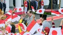 Kedatangan PM Shigeru Ishiba lalu disambut murid sekolah yang mengibarkan bendera Indonesia dan Jepang sambil mengucapkan kalimat selamat datang dalam bahasa Jepang. (Bay ISMOYO/AFP)