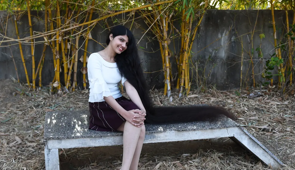 Gadis asal India, Nilanshi Patel (17), yang telah dianugerahi Guinness World Record 2019, berpose di kota Modasa, Ahmedabad, Minggu (19/1/2020). Rapunzel di dunia nyata ini mulai menumbuhkan rambutnya setelah mendapat potongan rambut yang jelek pada usia 6 tahun. (SAM PANTHAKY/AFP)