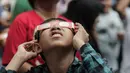 Pengunjung mengamati gerhana matahari cincin memakai kacamata khusus di Planetarium Taman Ismail Marzuki, Jakarta, Kamis (26/12/2019). Planetarium menyediakan sekitar 10 teleskop dan kacamata khusus agar pengunjung bisa menyaksikan gerhana matahari cincin dengan aman. (Liputan6.com/Faizal Fanani)