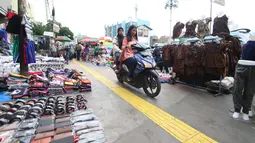 Pengendara motor melintas diatas trotoar yang samping kanan-kirinya dipenuhi pedagang kaki lima di Jalan Kebon Jati, Tanah abang, Sabtu (23/12). (Liputan6.com/Angga Yuniar)