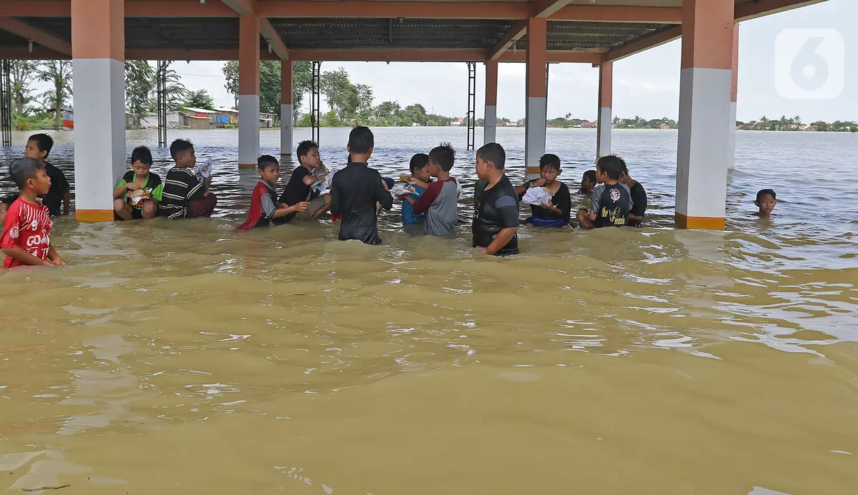 Anak-anak berkumpul saat banjir di Desa Sukalaksana Kabupaten Bekasi, Jawa Barat, Senin (22/02/2021). Hujan dengan intensitas tinggi turun sejak Jumat, 19 Februari 2021 mengakibatkan air di aliran sungai meluap. (Liputan6.com/Herman Zakharia)