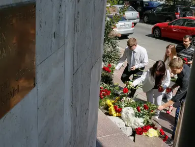 Sejumlah orang menaruh bunga di depan Kedutaan Besar Prancis di Kiev, Ukraina, (15/7). Karangan bunga tersebut untuk menghormati para korban teror Truk Maut saat perayaan hari Bastille di Nice. (REUTERS/Gleb Garanich)