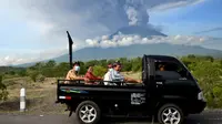 Sejumlah warga mengenakan masker menaiki mobil bak terbuka saat melewati Gunung Agung di Kabupaten Karangasem, Bali (27/11). (AFP/Sonny Tumbelaka)