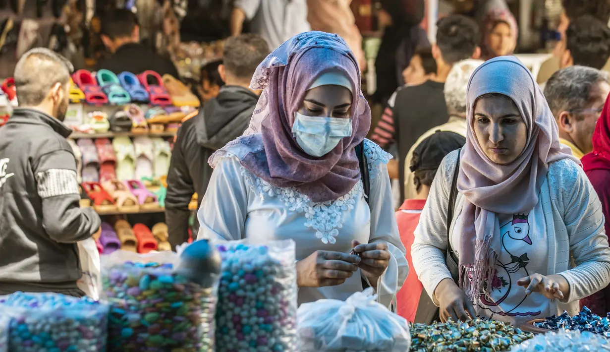 Para wanita berbelanja manisan menjelang Hari Raya  Idul Fitri di pasar utama Kota Qamishli, Provinsi Hasakeh, Suriah, Selasa (19/5/2020). Hari Raya Idul Fitri menandai berakhirnya bulan suci Ramadan. (DELIL SOULEIMAN/AFP)