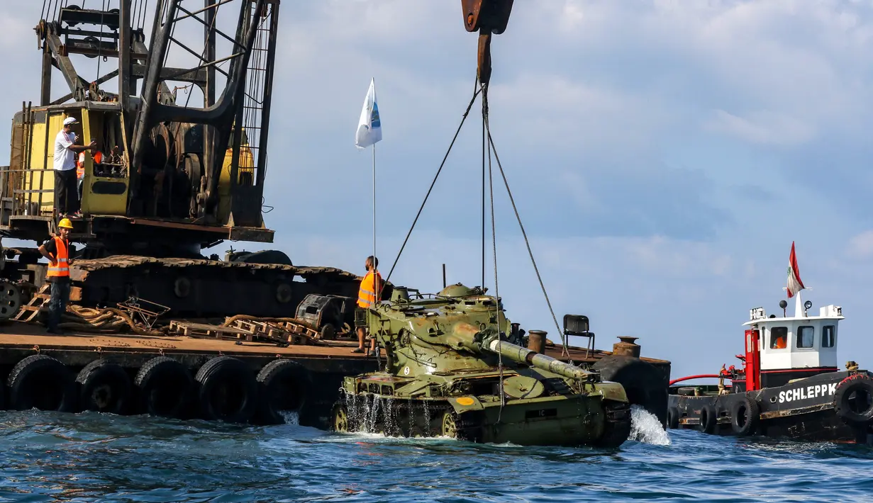 Aktivis lingkungan menurunkan tank lama ke dasar Laut Mediterania di lepas pantai kota pelabuhan Sidon, Lebanon, Sabtu (28/7). Para aktivis berharap rumput laut akan segera menutupi tank, yang merupakan hadiah dari militer tersebut. (AFP / Mahmoud ZAYYAT)