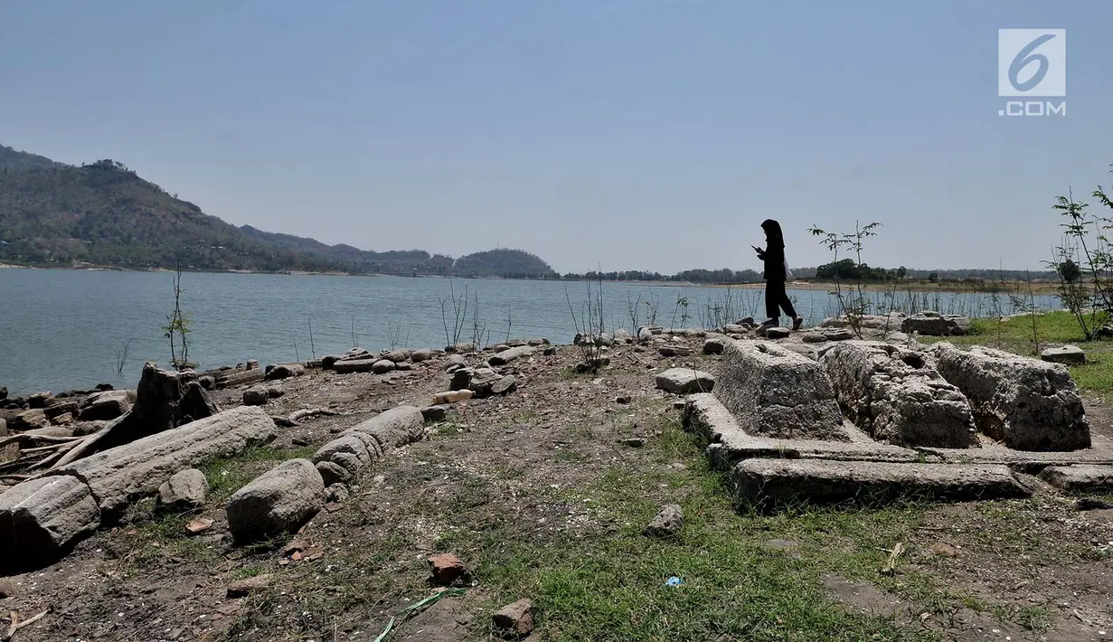 Wisatawan melintasi kompleks makam lama yang muncul ke permukaan Waduk Gajah Mungkur di Wonogiri, Selasa (2/9/2019). Setiap musim kemarau, makam lama milik warga yang rumahnya tergusur proyek pembangunan waduk pada tahun 1978-1980 itu muncul saat volume air waduk menyusut (merdeka.com/Iqbal Nugroho)