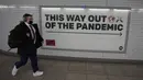 Seorang pejalan kaki melewati sebuah iklan di terowongan stasiun bawah tanah di London, Kamis (20/1/2022). Pemerintah Inggris mengakhiri pembatasan COVID-19, termasuk mandat masker, bekerja dari rumah dan paspor vaksin mulai Kamis. (AP Photo/Kirsty Wigglesworth)