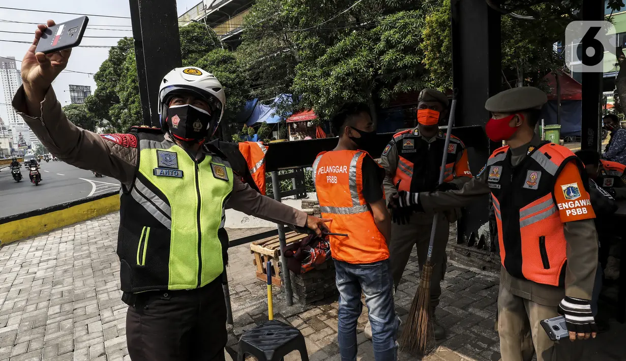 Petugas memotret warga pelanggar Pembatasan Sosial Berskala Besar (PSBB) yang terjaring razia masker di wilayah Tanah Abang, Jakarta, Senin (14/9/2020). Razia tersebut guna menekan kasus penyebaran COVID-19 di Jakarta pada masa PSBB. (Liputan6.com/Johan Tallo)