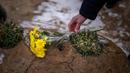 Seorang pria meletakkan bunga di makam seorang kerabatnya dalam upacara peringatan satu tahun dimulainya perang Rusia-Ukraina, di sebuah pemakaman di Bucha, Ukraina, Jumat, 24 Februari 2023. (AP Photo/Emilio Morenatti)