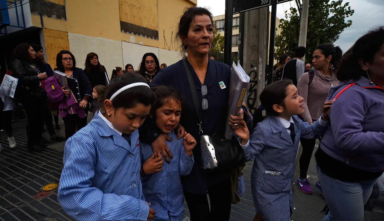 Sejumlah anak dievakuasi dari dalam gedung saat terjadi gempa di Vina del Mar, Chile (24/4). Pemerintah Chile menghimbau warga menyelamatkan diri ke tempat lebih tinggi dan menjauhi pantai. (AFP Photo/Francesco Degasperi)