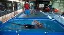 Leslie Amat, seorang atlet triathlon Kuba, berenang di kolam kecil di bawah pengawasan pelatihnya Dioseles Fernandez di teras rumahnya di Havana, Senin (20/4/2020). Atlet Kuba tak bisa berlatih di fasilitas olahraga seperti biasanya selama pademi corona. (AP /Ismael Francisco)