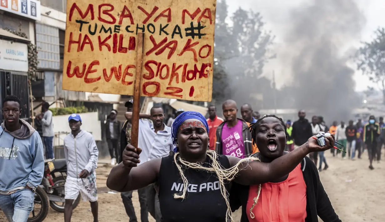 Pengunjuk rasa membawa plakat dalam bahasa Swahili mengacu pada Presiden Kenya William Ruto yang membaca "Ruto, apa yang salah dengan pemikiran Anda, kami muak" di lingkungan Kibera di Nairobi, Kenya Rabu, 12 Juli 2023.(AP Photo/Samson Otieno)