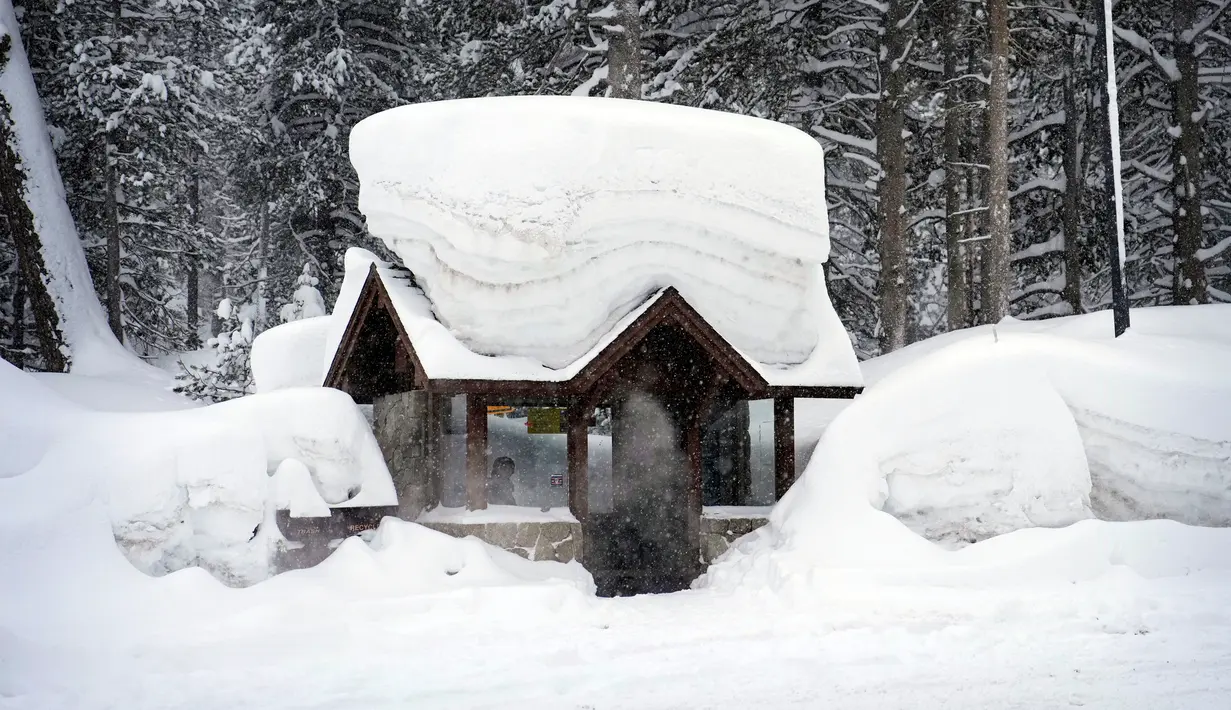 Seseorang duduk di halte bus yang tertutup salju di Olympic Valley, California, Amerika Serikat, 24 Februari 2023. California dan bagian lain di Barat menghadapi salju lebat dan hujan dari badai musim dingin terbaru yang melanda Amerika Serikat. (AP Photo/John Locher)