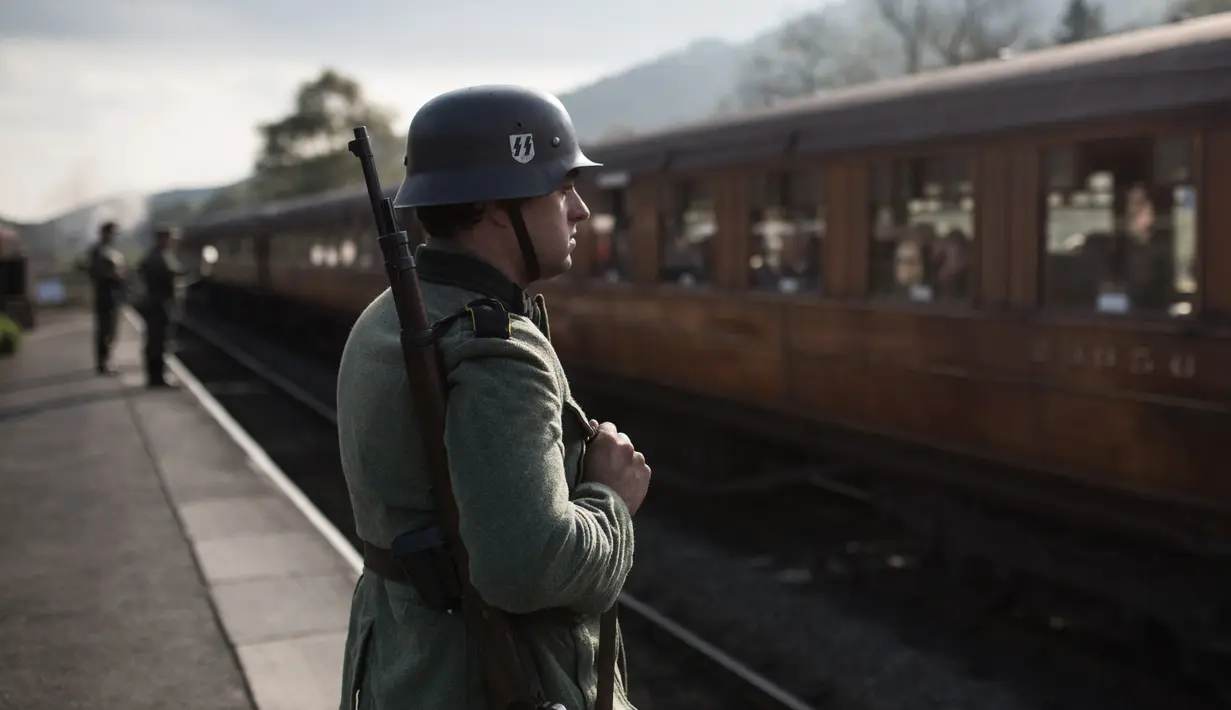 Reenactor Perang Dunia II mengenakan pakaian tentara Jerman berdiri di dekat kereta uap saat mengikuti 'Railway in Wartime Event' yang ke 25 di Pickering, Inggris (15/10). (AFP Photo/Oli Scarff)